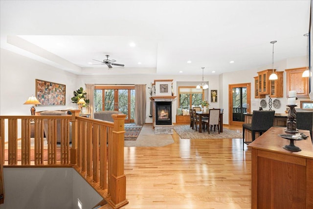 2222 White Oak Ct, Hudson, WI 54016 - living room with light wood-style floors, a ceiling fan, recessed lighting, a tray ceiling, and a glass covered fireplace