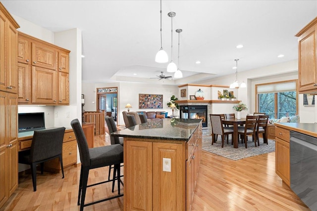 2222 White Oak Ct, Hudson, WI 54016 - kitchen featuring dishwasher, light wood finished floors, a center island, a kitchen bar, and a glass covered fireplace