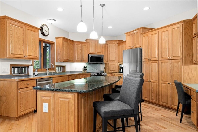 2222 White Oak Ct, Hudson, WI 54016 - kitchen featuring appliances with stainless steel finishes, a center island, light wood-style floors, a kitchen bar, and recessed lighting