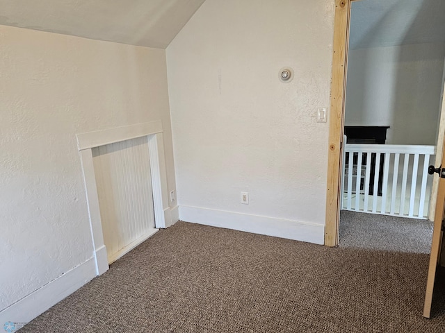 bonus room featuring lofted ceiling, a textured wall, carpet floors, and baseboards