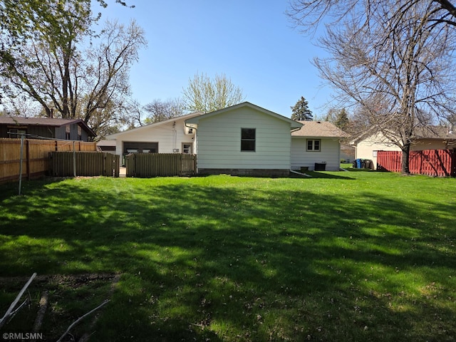 back of property with a lawn, fence, and a garage