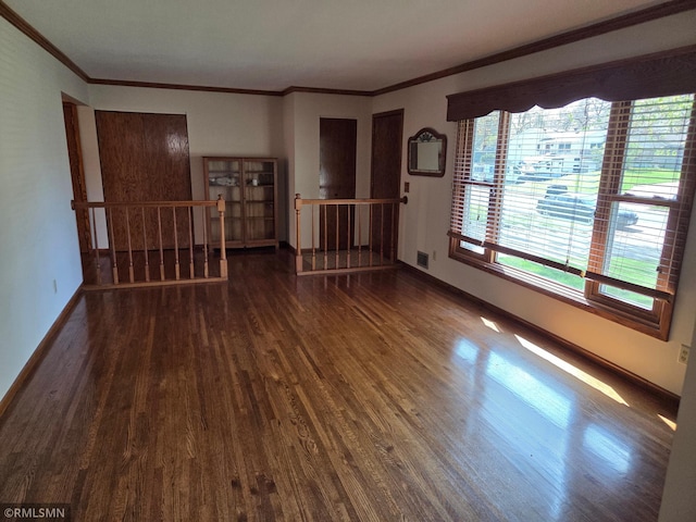 empty room with baseboards, ornamental molding, visible vents, and wood finished floors