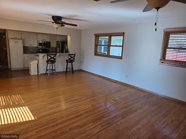 living room with a ceiling fan, baseboards, and wood finished floors