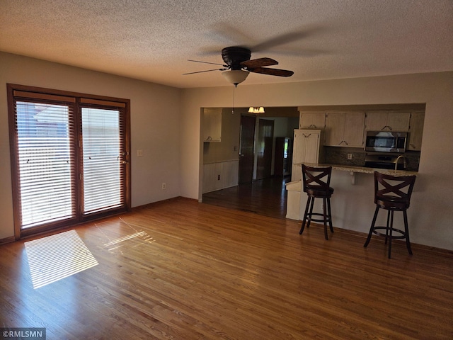 living area with a healthy amount of sunlight, ceiling fan, and dark wood-style floors