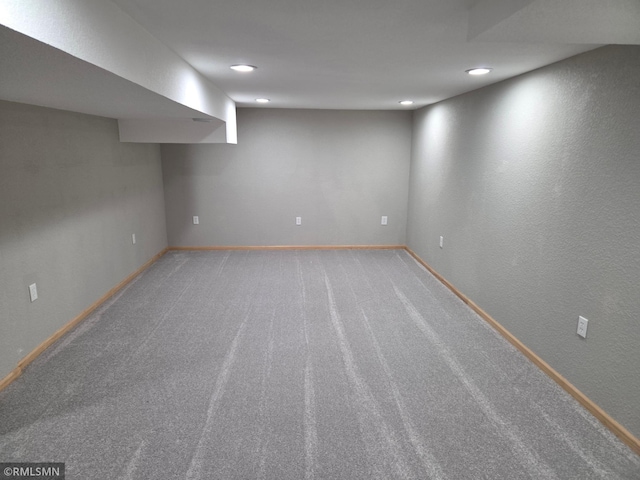 finished basement with baseboards, recessed lighting, carpet, and a textured wall