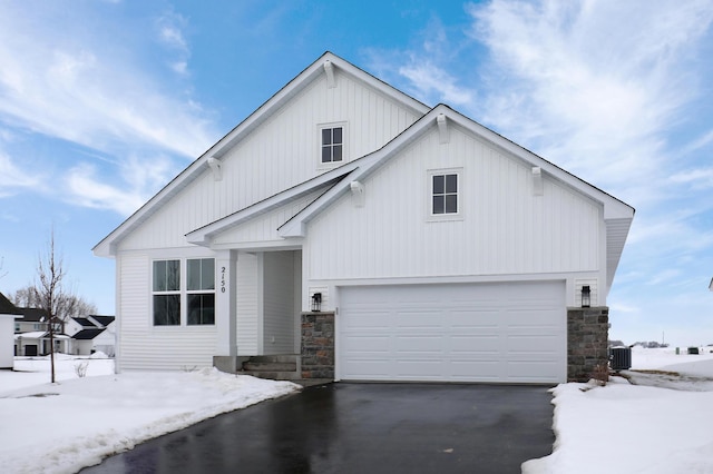 view of front of home featuring an attached garage, central AC, stone siding, board and batten siding, and driveway