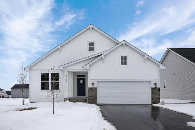 view of front of house with a garage, board and batten siding, stone siding, and aphalt driveway