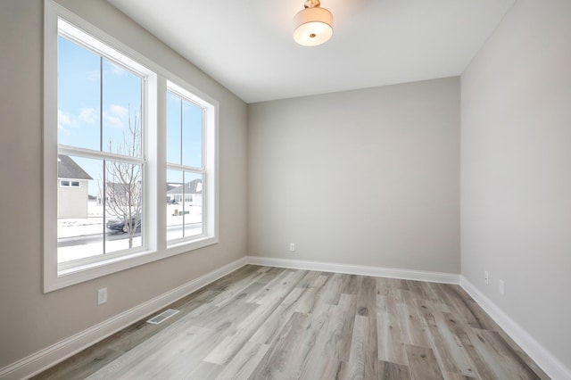 spare room with baseboards, light wood-style flooring, and visible vents