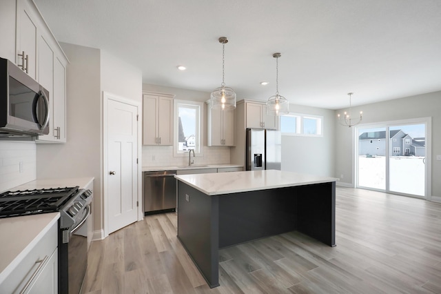 kitchen featuring decorative backsplash, light countertops, a sink, appliances with stainless steel finishes, and a notable chandelier