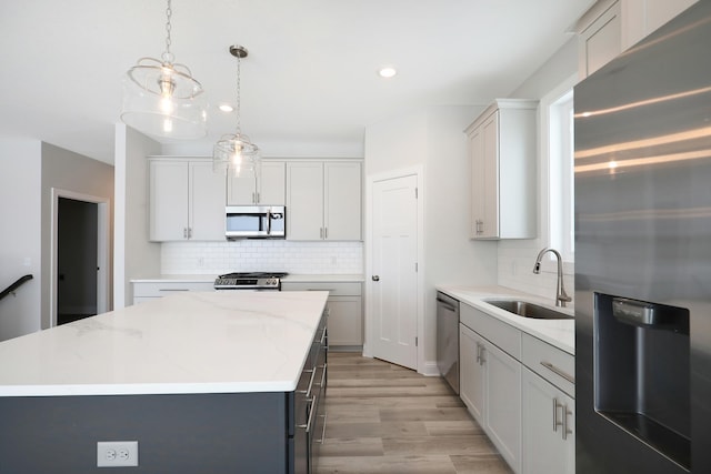 kitchen with decorative backsplash, a center island, a sink, light wood-style flooring, and stainless steel appliances