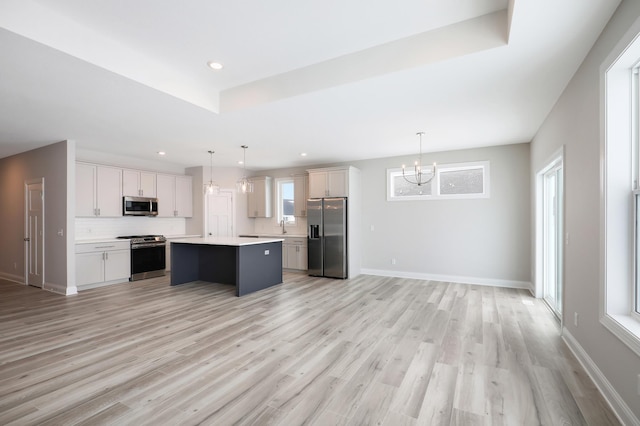 kitchen featuring a kitchen island, appliances with stainless steel finishes, light countertops, open floor plan, and an inviting chandelier