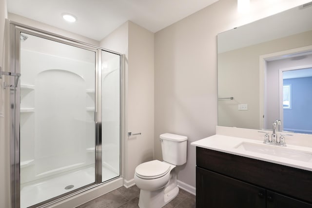 bathroom featuring a shower stall, vanity, tile patterned floors, baseboards, and toilet