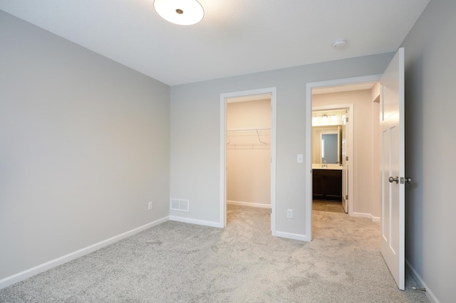 unfurnished bedroom with a walk in closet, carpet, baseboards, visible vents, and a closet