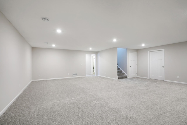 finished basement featuring visible vents, light carpet, baseboards, stairway, and recessed lighting