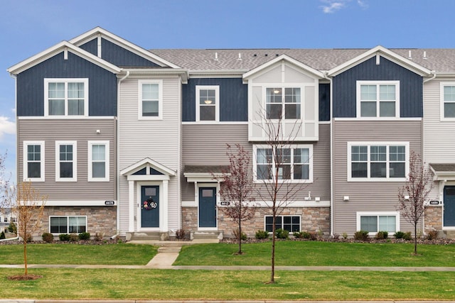 multi unit property featuring entry steps, stone siding, and a front yard