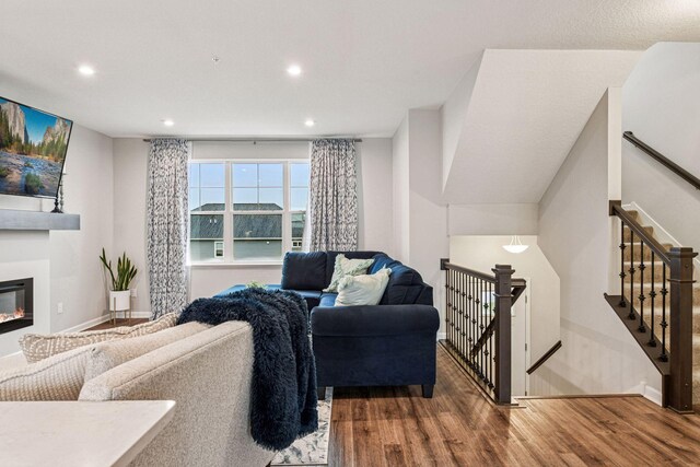 living area featuring wood finished floors, recessed lighting, a glass covered fireplace, and baseboards