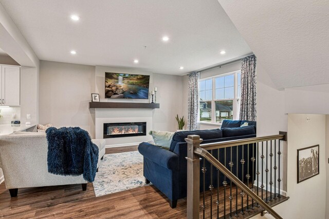 living area featuring wood finished floors, recessed lighting, and a glass covered fireplace