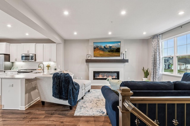 living area with dark wood-style flooring, recessed lighting, and a glass covered fireplace
