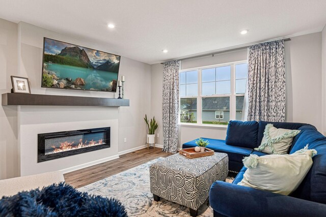 living room with wood finished floors, recessed lighting, a glass covered fireplace, and baseboards