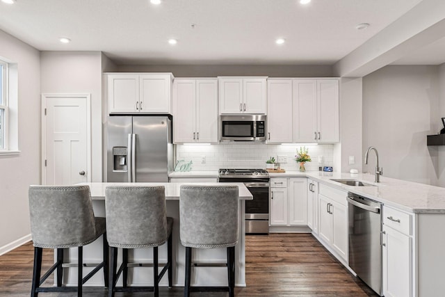 kitchen featuring appliances with stainless steel finishes, a sink, decorative backsplash, dark wood-style floors, and recessed lighting