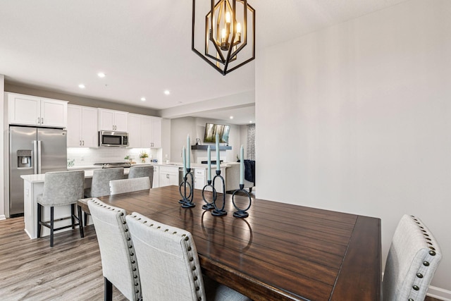 dining area featuring light wood-style floors, recessed lighting, and a chandelier