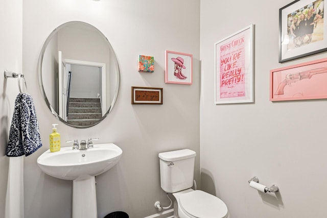 half bathroom featuring toilet, baseboards, and a sink