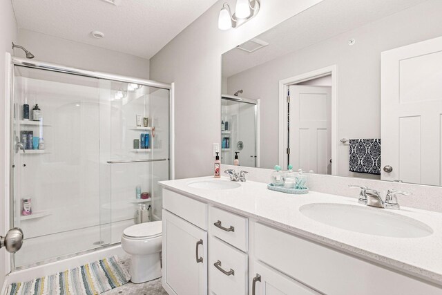 bathroom with a stall shower, toilet, and double vanity