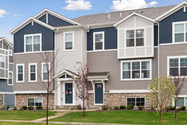 view of front of house featuring entry steps, stone siding, and a front yard