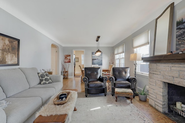 2102 Pinehurst Ave, Saint Paul, MN 55116 - living area with wood finished floors, arched walkways, a stone fireplace, and baseboards