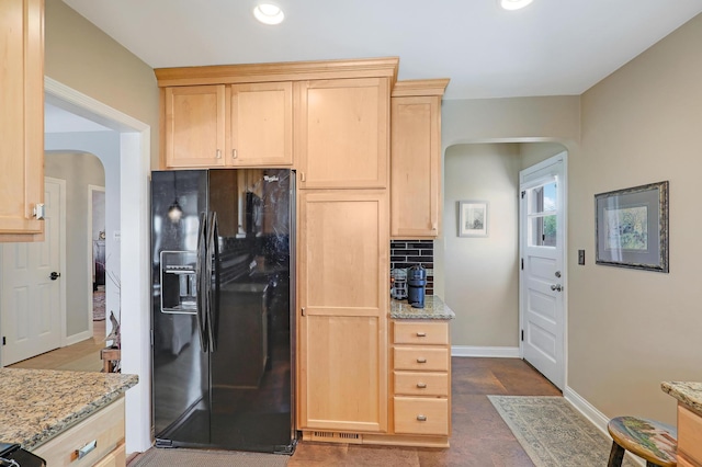 2102 Pinehurst Ave, Saint Paul, MN 55116 - kitchen with black fridge, arched walkways, light brown cabinetry, backsplash, and light stone counters