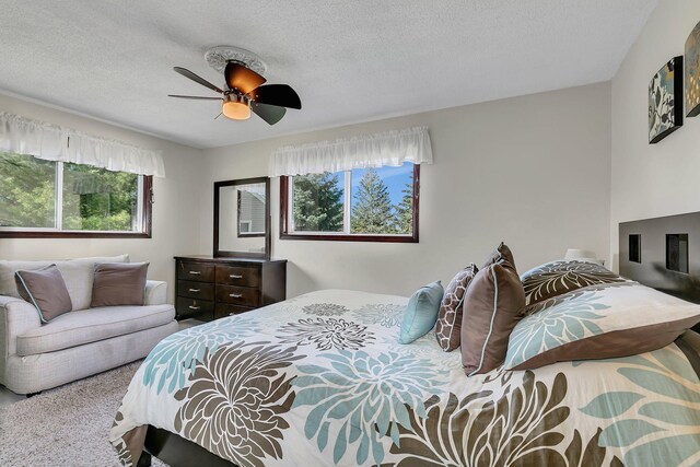 carpeted bedroom with a textured ceiling and a ceiling fan