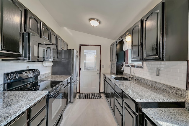 kitchen with lofted ceiling, black appliances, tasteful backsplash, and a sink