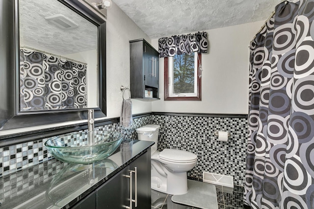 full bath featuring a textured ceiling, toilet, wainscoting, visible vents, and vanity