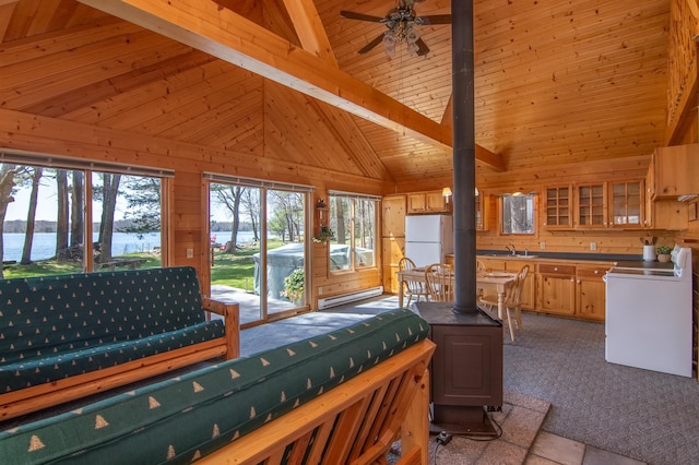 carpeted bedroom featuring beamed ceiling, wood walls, a sink, and a wood stove