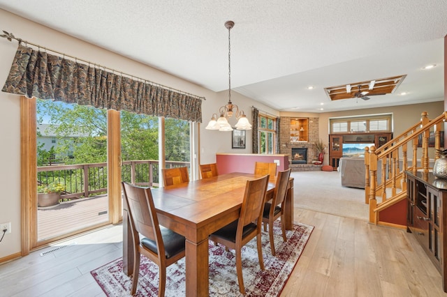 2374 Thrush St, Shakopee, MN 55379 - dining area featuring a brick fireplace, healthy amount of natural light, light wood finished floors, a chandelier, and recessed lighting