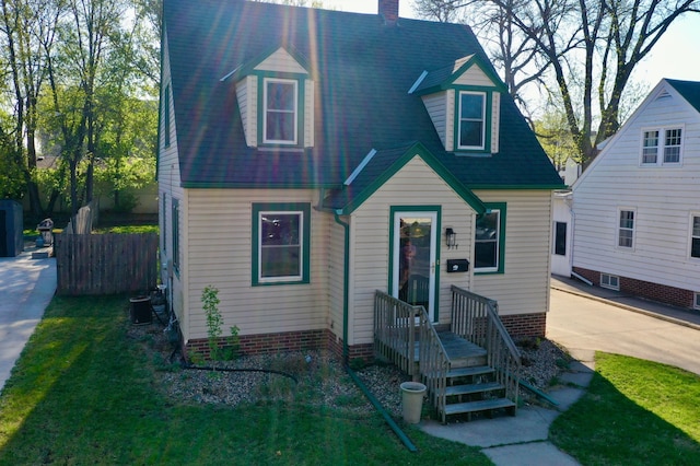 cape cod home featuring fence, a chimney, and a front yard