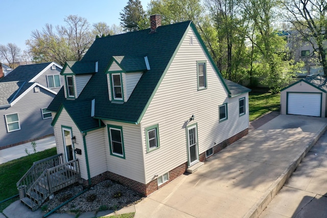 view of front of property featuring a garage, an outdoor structure, a chimney, and roof with shingles