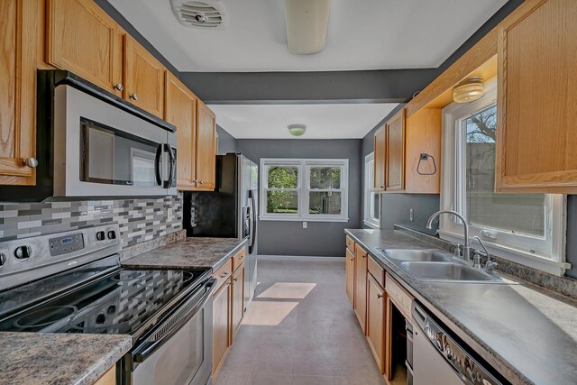 kitchen featuring stainless steel appliances, a sink, plenty of natural light, and baseboards