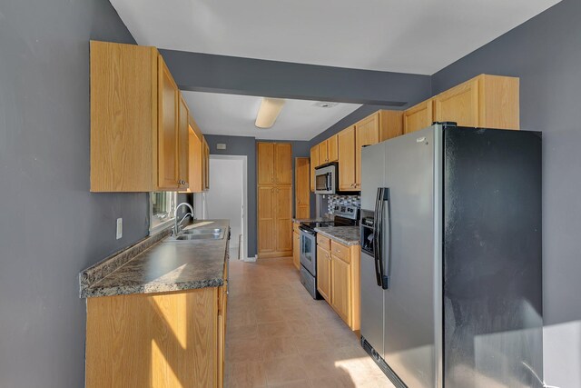 kitchen featuring appliances with stainless steel finishes, a sink, decorative backsplash, dark countertops, and light floors