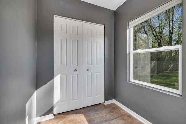 unfurnished bedroom with dark wood-type flooring, a closet, and baseboards
