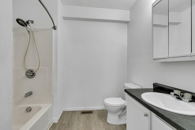 full bath featuring wood finished floors, toilet, vanity,  shower combination, and baseboards