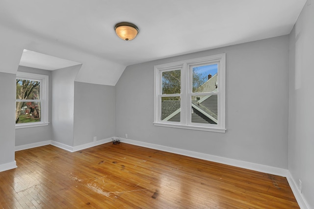 bonus room with lofted ceiling, hardwood / wood-style flooring, baseboards, and plenty of natural light