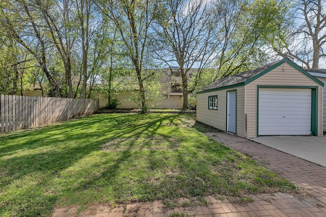 view of yard with an outdoor structure, concrete driveway, and a garage