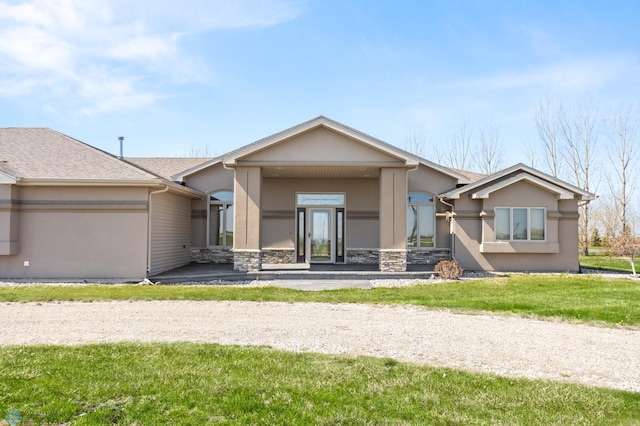 view of front facade with stucco siding, stone siding, and a front yard