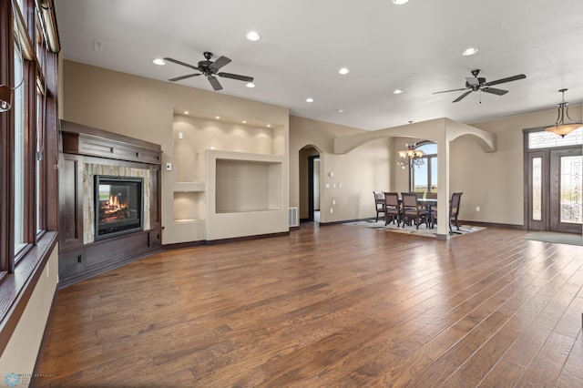 unfurnished living room with arched walkways, ceiling fan, wood finished floors, recessed lighting, and baseboards