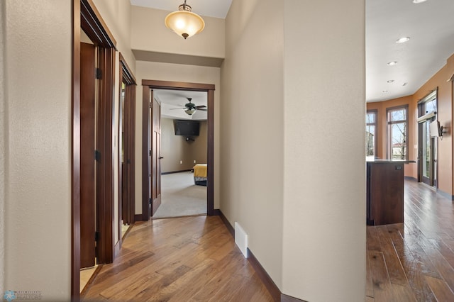 hall with hardwood / wood-style flooring, baseboards, and recessed lighting