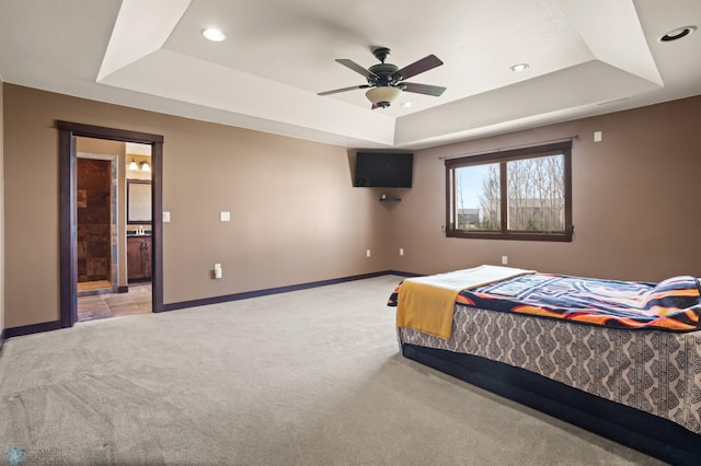 bedroom featuring a tray ceiling, light carpet, baseboards, recessed lighting, and ensuite bath