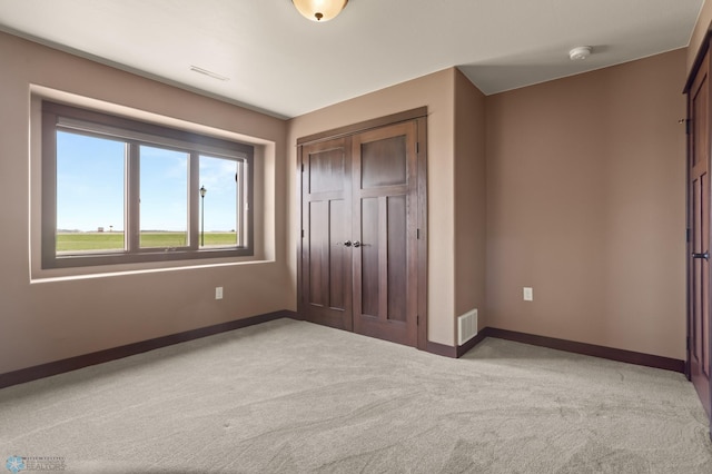 unfurnished bedroom featuring light colored carpet, baseboards, and a closet