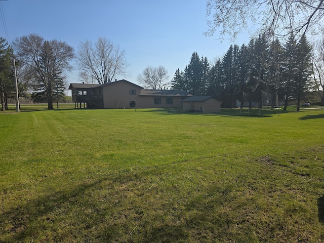 view of yard with a trampoline, an outdoor structure, and a storage unit