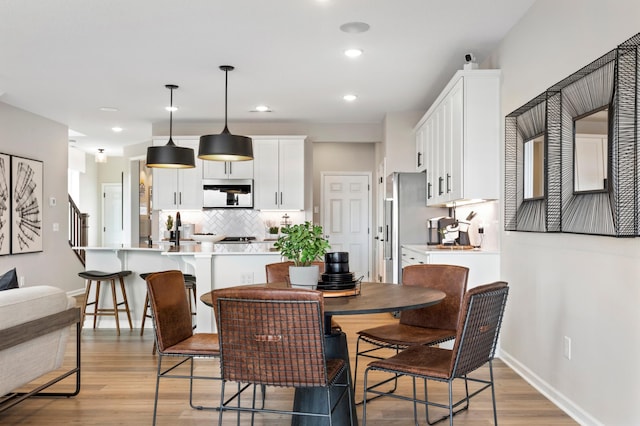 dining room with baseboards, recessed lighting, and light wood finished floors